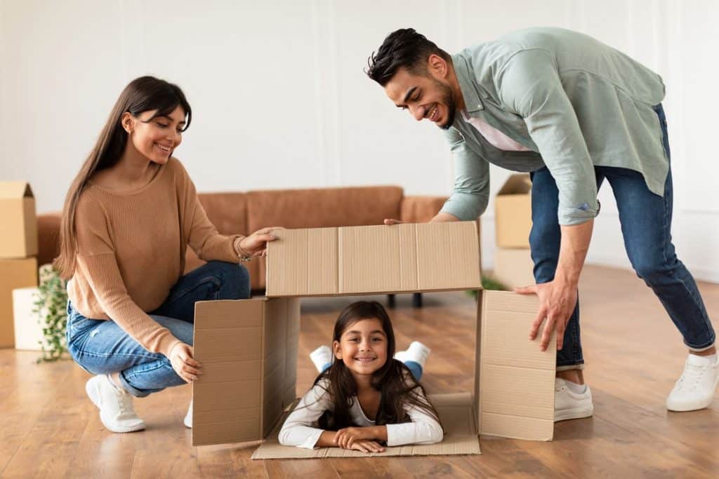 happy family new tenants with kid sitting in box